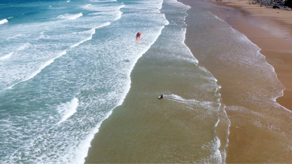 Newquay Cornwall drone photography by JStudios: surfers and waves on a sandy beach