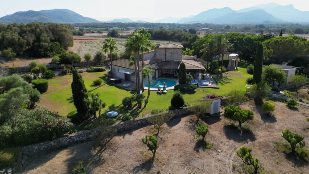 Aerial drone photo of a villa with a swimming pool, gardens and mountains behind
